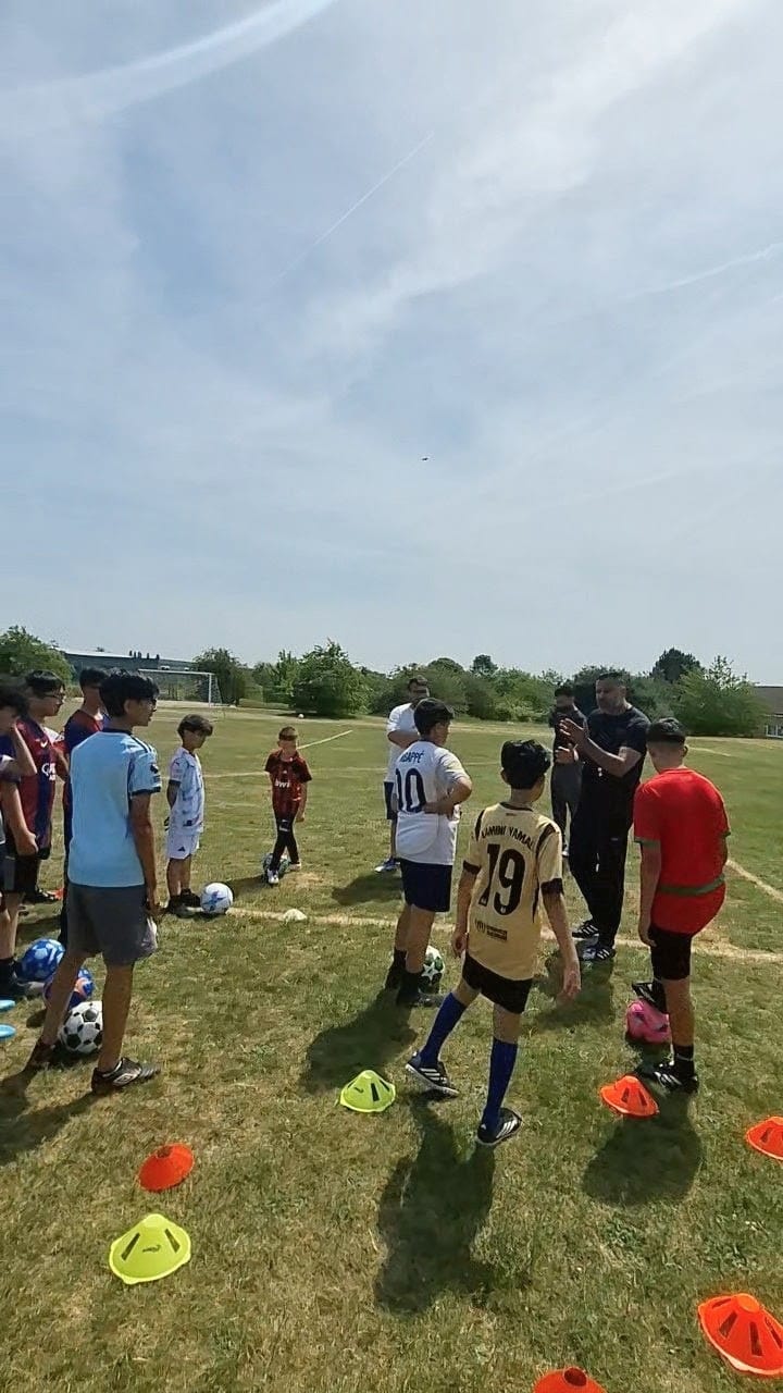 Active Goals Football coaching session with young players gathered round for a drill briefing on the field